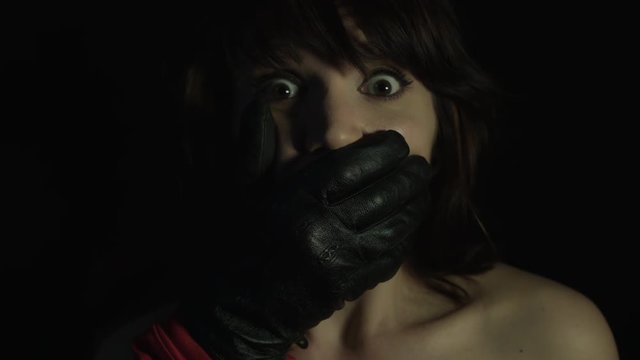 4k shoot of a woman in studio with a hand closing her mouth
