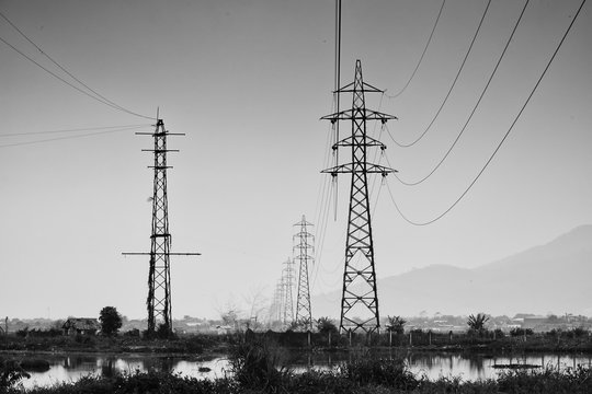 Transmission tower, electricity pylon or a power pylon, standing majestically lined up to the horizon, photo in black and white