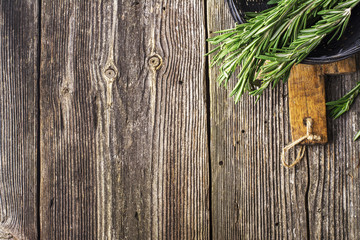 Fresh cut rosemary in a bundle in  black wicker basket on  simple dark wooden background. View from above. selective focus