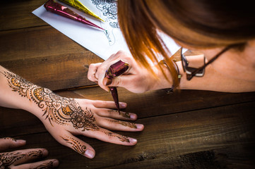 woman mehendi artist painting henna on the hand