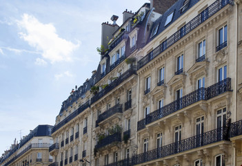 Buildings at 2nd arrondissement in Paris showing 19th century architectural style. Iron, ornamental balconies and plants are in the view.
