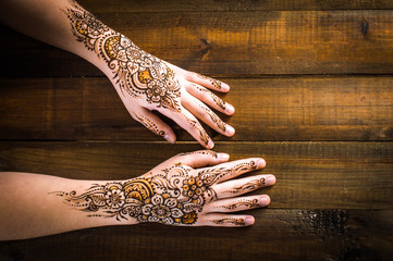 mehendi on the hands on the wooden background