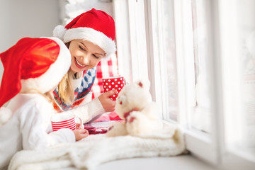 family mother and child girl talking and drinking hot tea at win
