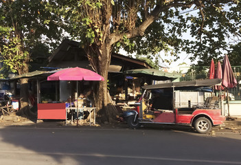 Obraz premium The Tuk-tuks park at the temporary station wait for the passenger. The Tuk-tuk is the nickname given to a three-wheeled miniature truck that provide a cheap vehicle for taxiing services .