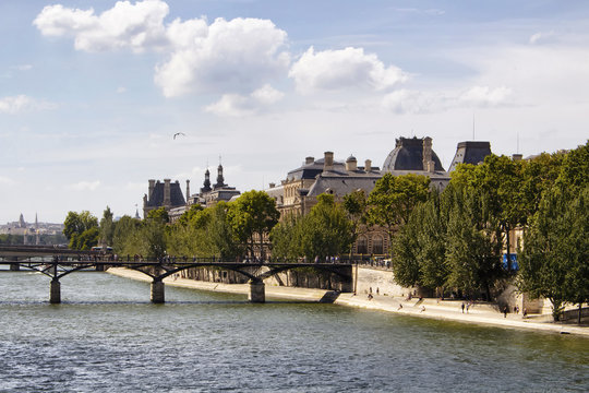 View of Seine river, Pont des Arts, trees and buildings in Paris.