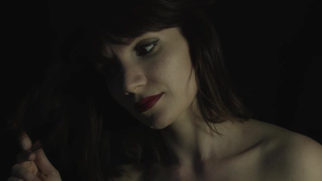 4k shoot of a woman in studio playing with her hairs and looking