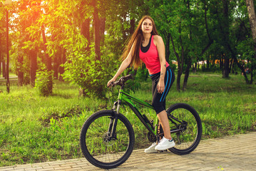 Sports happy girl over a bicycle in the park