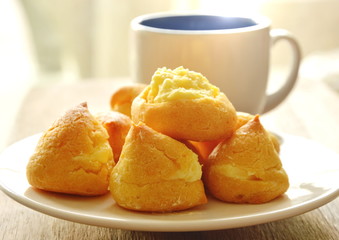 vanilla cream puff on dish and coffee cup