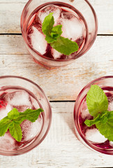 red juice with mint and ice in a glass on a wooden background