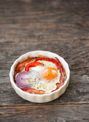 Baked eggs with bacon, red pepper and onion