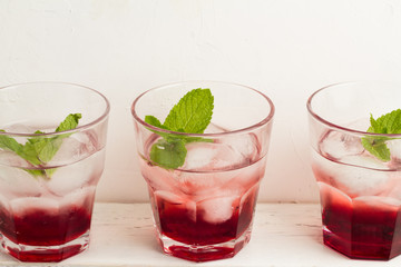 Three glasses with red drink with mint and ice on a white background