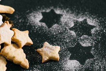 Traditional Christmas cookies powdered with sugar on black table