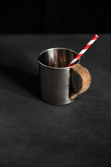 Hipster metal cup with red white straw on black table