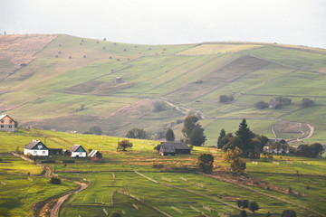 Alpine village in mountains. Smoke and haze over hills