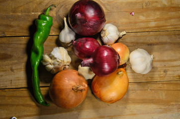 Onion, pepper and garlic on a wooden table