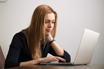 Businesswoman sitting at her workstation in office and working by notebook