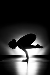 Woman doing yoga crow pose silhouette black and white