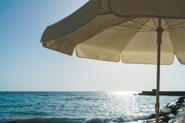 Relaxing view of the sea from under a beach umbrella in the counter-light of the sun, the glare on...