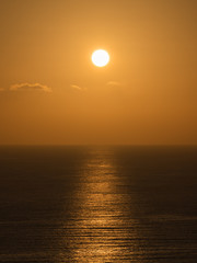 A view of a golden sunset over the sea. The light of the sun reflected in the water as the beam path.