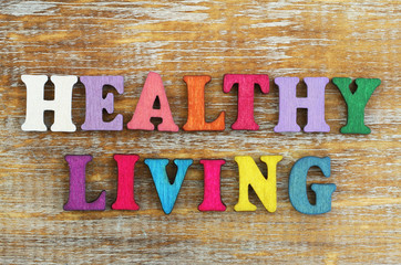 Healthy living written with colorful letters on rustic wooden surface
