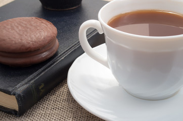 White cup of hot cocoa and a chocolate biscuit