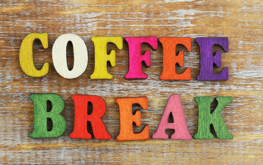 Coffee break written with colorful letters on rustic wooden surface
