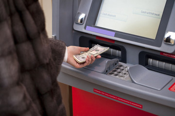 Woman hand showing dollar banknotes in front of the atm