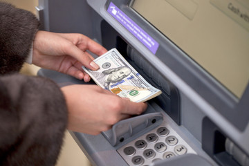 Woman hand showing dollar banknotes in front of the atm