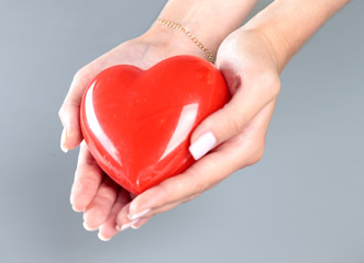 Young woman doctor holding a red heart, isolated on white