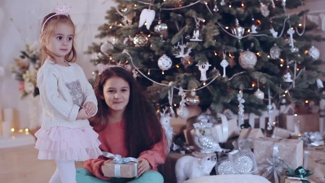 Two girls near a Christmas tree with gifts