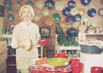 Smiling mature female holding  ceramic cookware