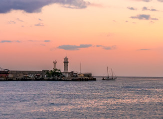 Fototapeta premium The lighthouse at the seaport of Yalta on the sunset background