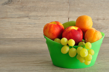 A variety of fruit in a green plastic bucket