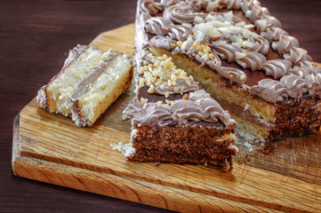 Sliced cake with cream on a round wooden cutting board - closeup