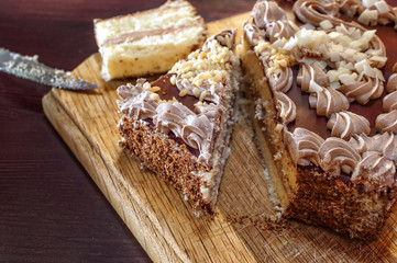 Sliced cake with cream on a round wooden cutting board - closeup