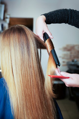 Fototapeta premium Woman hairdresser using curling iron.