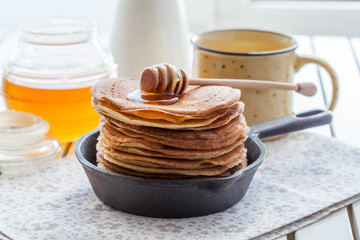 pancakes in a cast iron skillet with honey © natalyadolgova