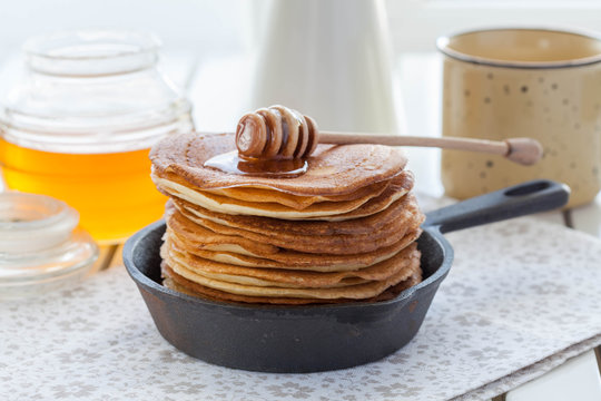 pancakes in a cast iron skillet with honey