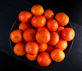 Fresh mandarin Tangerines oranges in black bowl