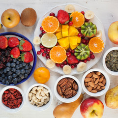 Vegan breakfast: variety of fruits, nuts and berries on the white wooden table, selective focus, square