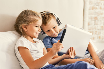 Cute brother and sister enjoying tablet at home