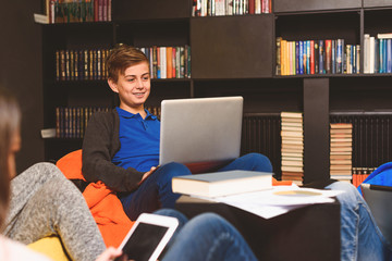 Smiling teenager typing on laptop