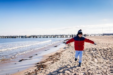 Boy in red jacket running on beach