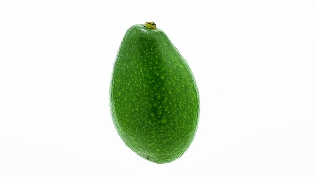 Green avocado suspended in the air rotates in loop    