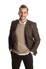 A attractive man in his 20s standing against a white background wearing a brown suit with a sweater and white shirt.