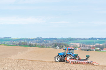 Obraz premium Large view on the tractor harrowing the field in spring season