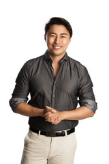 Relaxed good looking man standing against a white background wearing a grey shirt, smiling looking at camera.