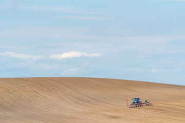 Large view on the tractor harrowing the field in spring season