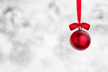 Red Christmas ball with red ribbon hanging on spakles bokeh back