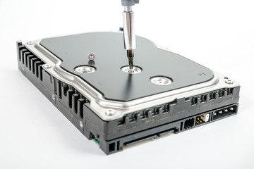 Cropped screwdriver unscrews the 3.5 inch hard drive cover screw. Isolated on white background.